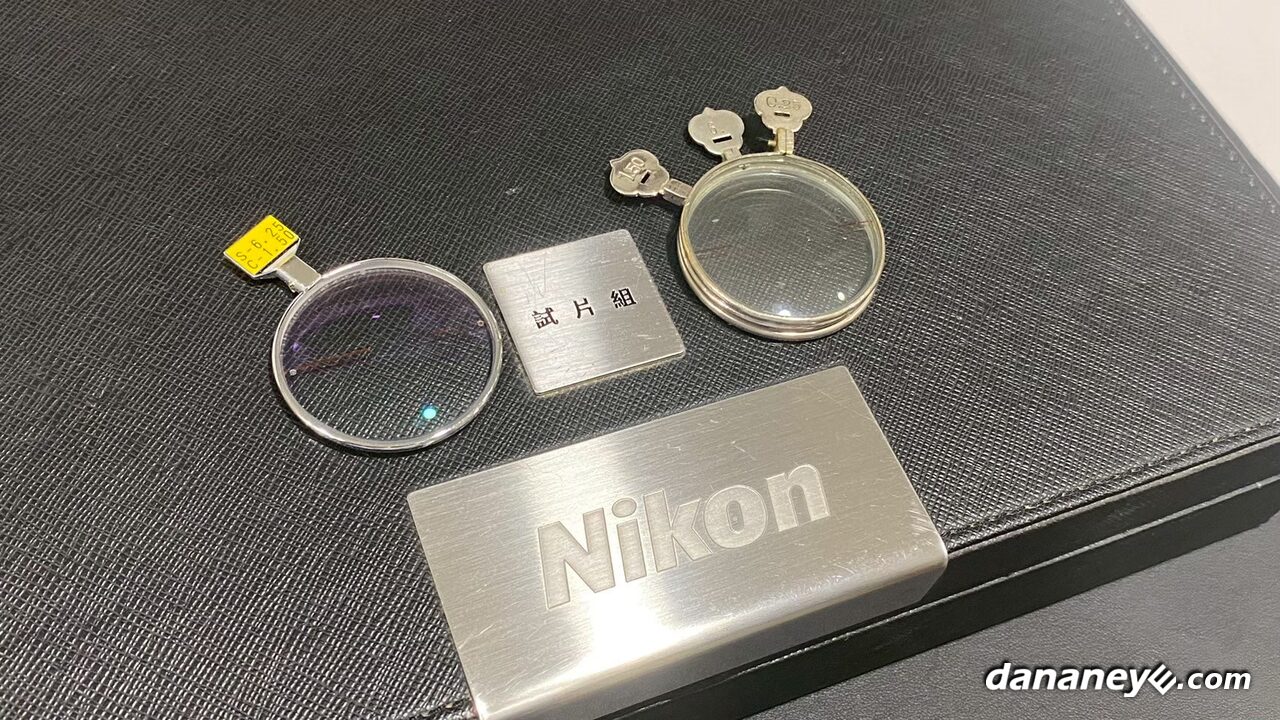 Nikon 銘牌與試片組字樣的黑色皮盒,旁邊放著兩片單片試片 Nikon 銘牌與試片組字樣的黑色皮盒,旁邊放著兩片單片試片